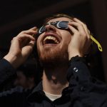 Proctors staff members share Moon Pies and specialty glasses while watching the peak of the eclipse behind the theatre in Schenectady Friday, August 21, 2017.